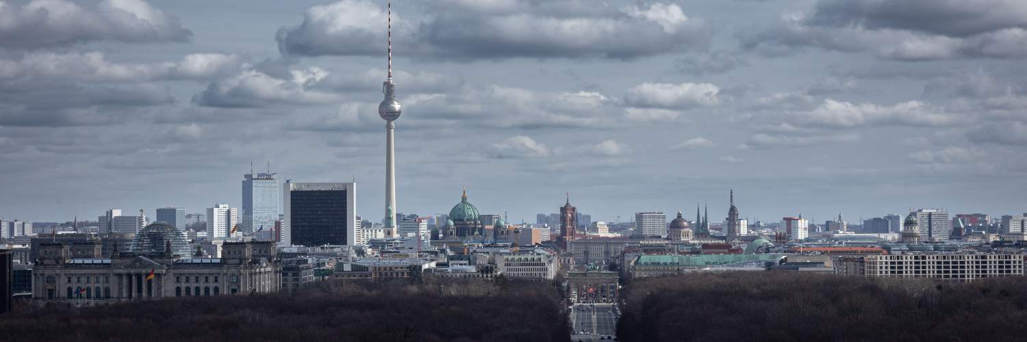 A distant view of the Berlin skyline featuring the iconic Berlin TV Tower against a clear blue sky.