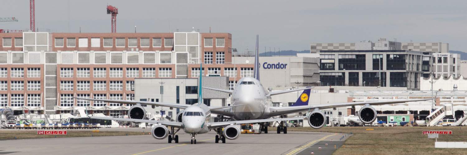 Two large airplanes taxiing on the runway at Frankfurt Airport Terminal, showcasing airport activity and infrastructure.