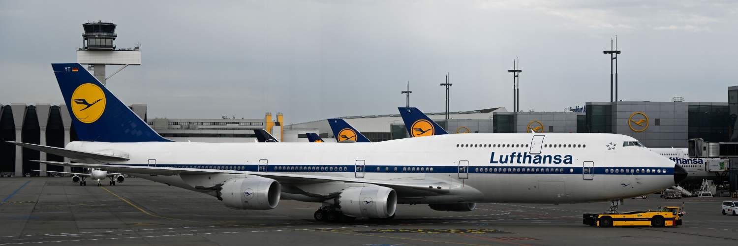 A commercial jetliner stationed at Frankfurt Airport, surrounded by airport infrastructure and service vehicles.