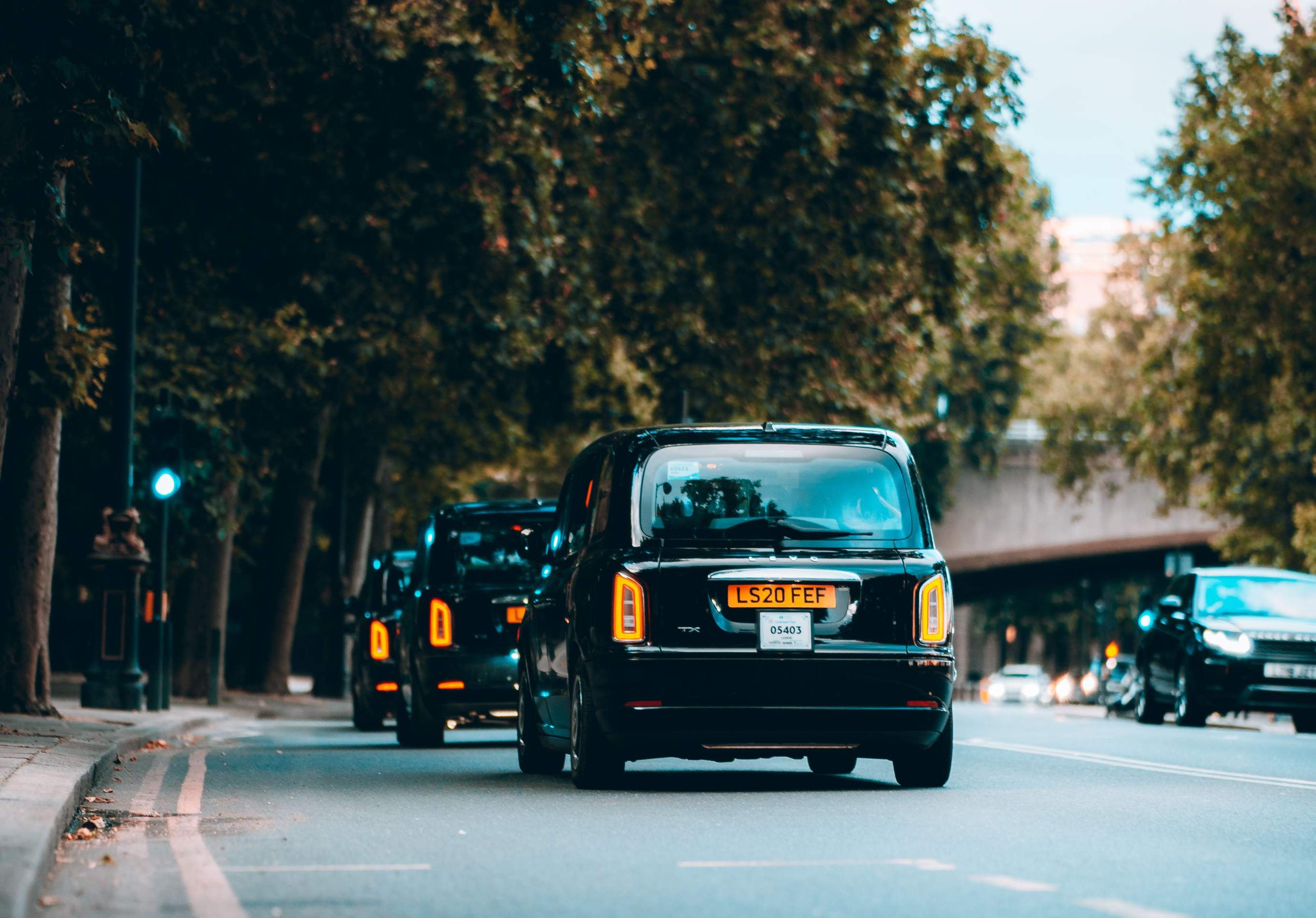 Black taxis driving along a busy city street near Heathrow Airport, showcasing urban transportation.