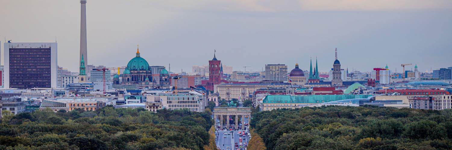 Berlin skyline featuring the Brandenburg Gate prominently in the foreground with the Fernsehturm in the background.