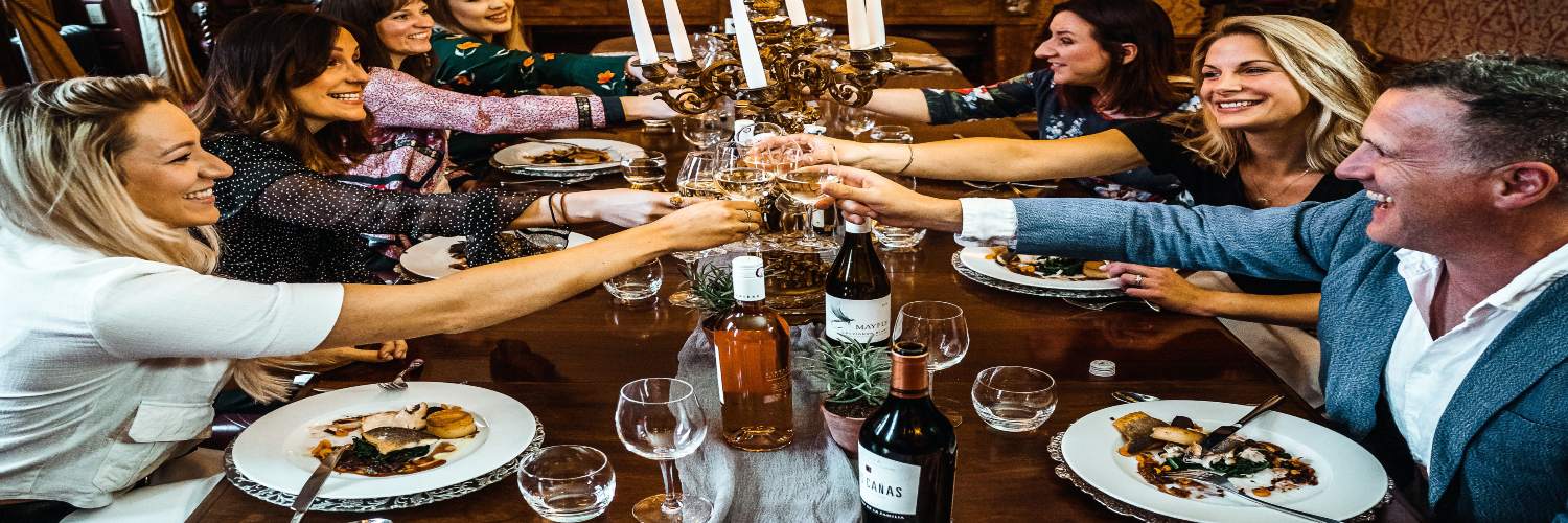 A group of people raising glasses in a toast at a festive dinner table in London.