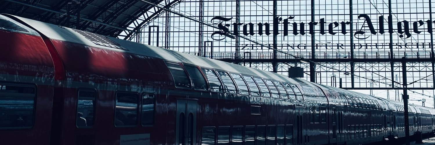 A train stands at Frankfurt Hauptbahnhof, highlighting the station's grandeur and the busy environment surrounding it.