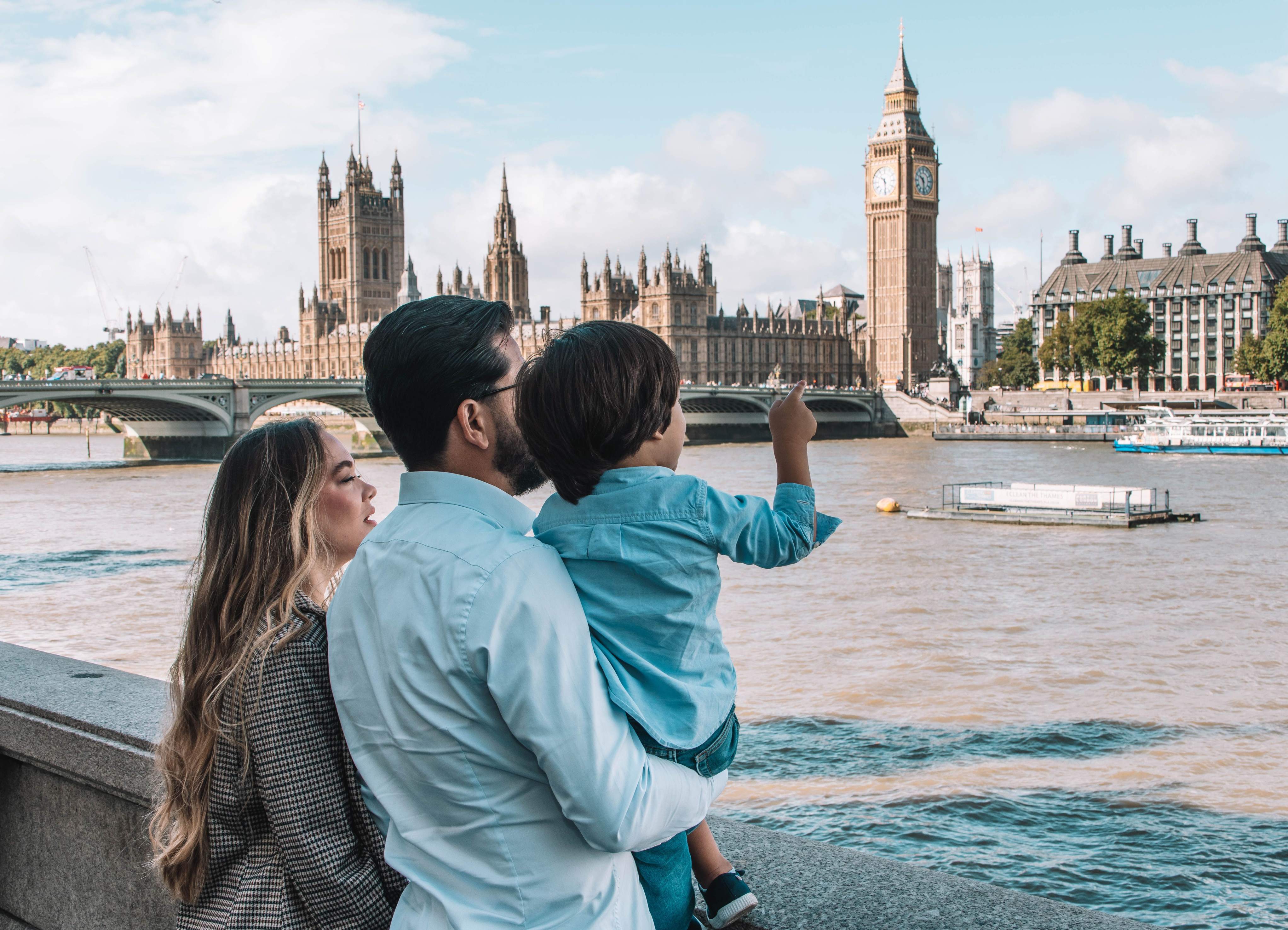 A family poses in front of the Parliament building in London, showcasing the iconic architecture and vibrant atmosphere.