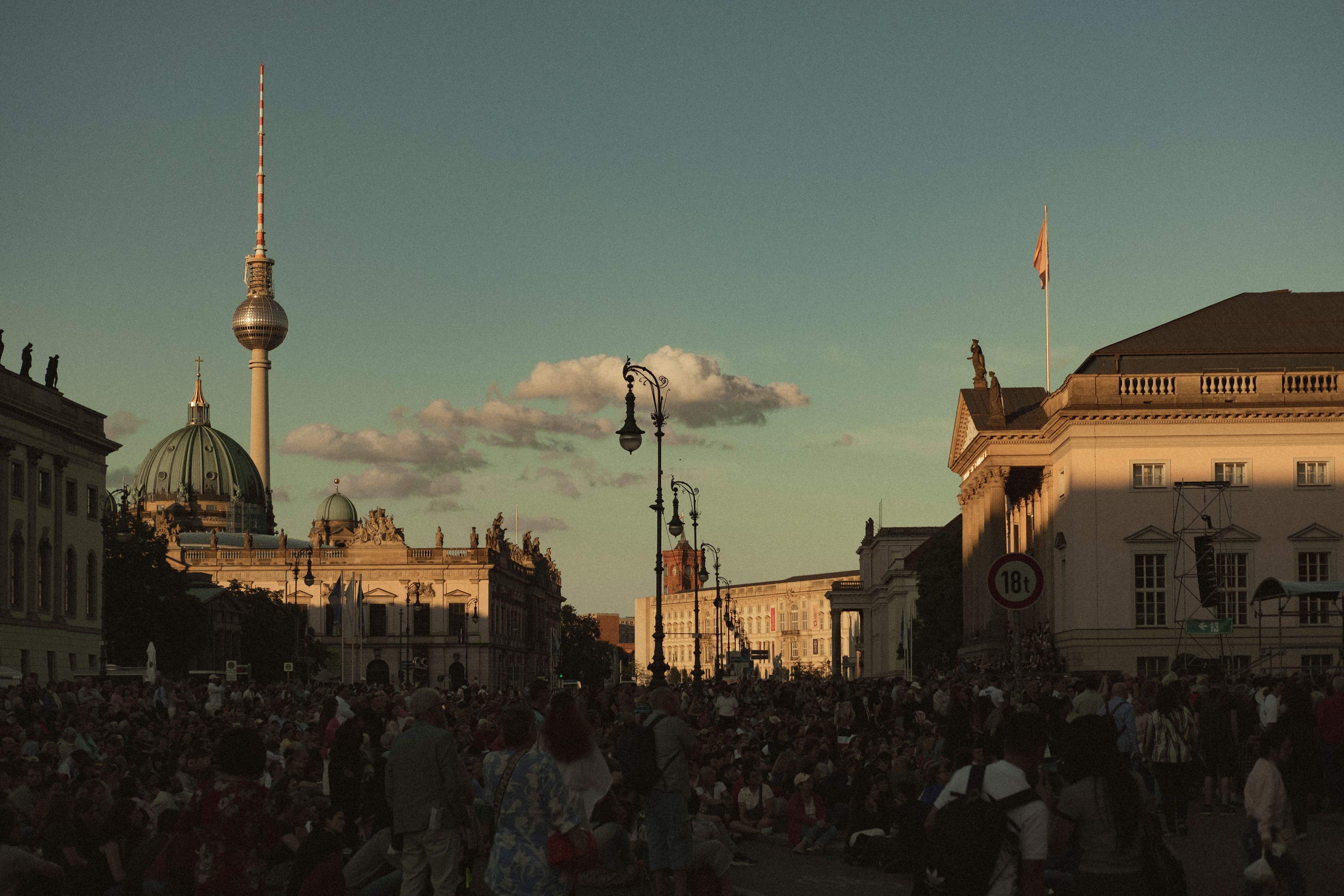 A crowd gathers in front of Berlin's iconic TV Tower, showcasing the vibrant atmosphere of the city.