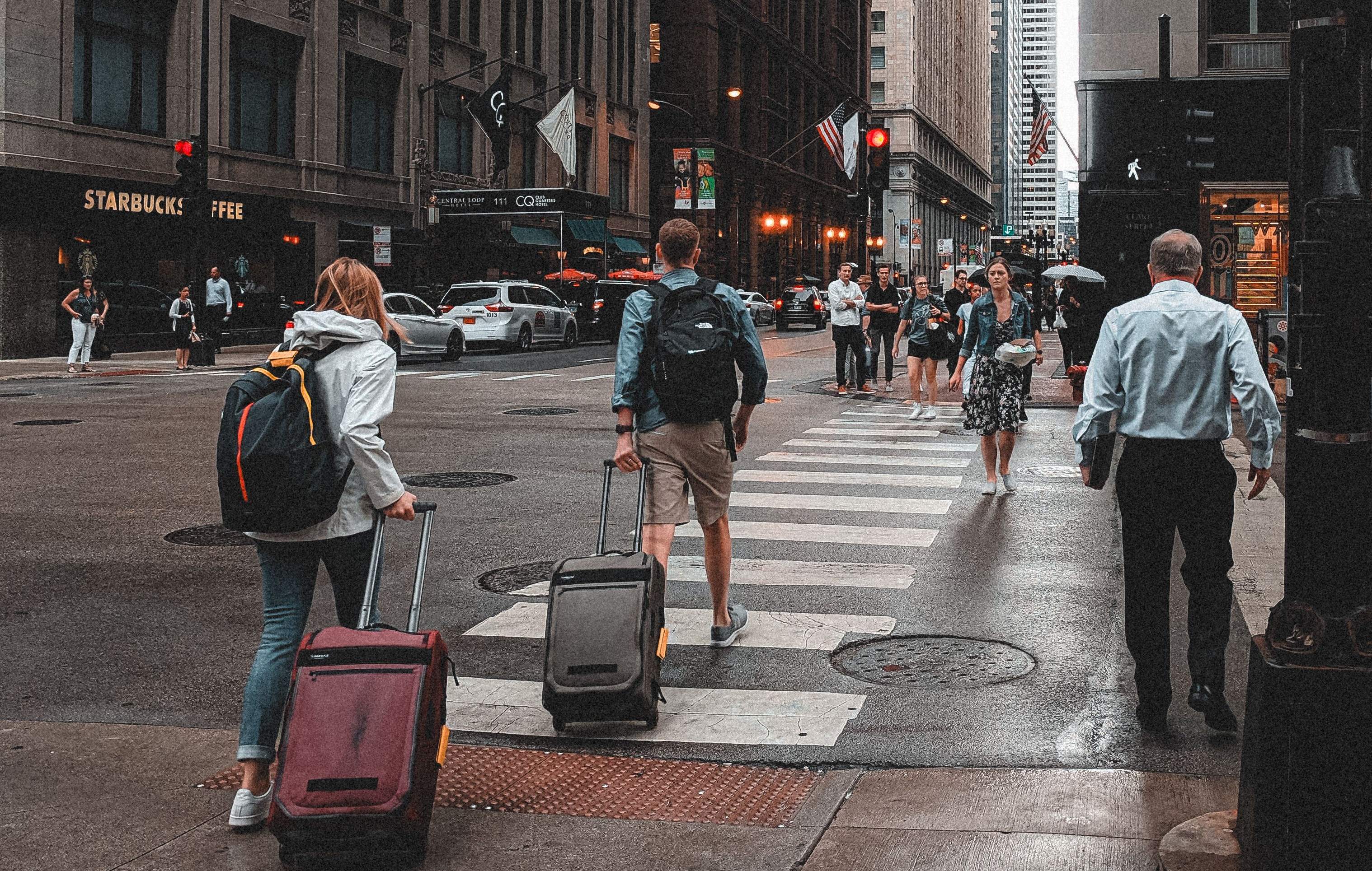 A group of business travelers navigating a busy Frankfurt street, each with luggage in tow.
