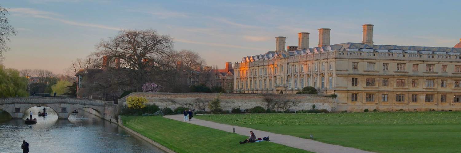 The River Cam flows through Cambridge, surrounded by lush greenery and historic buildings along its banks.