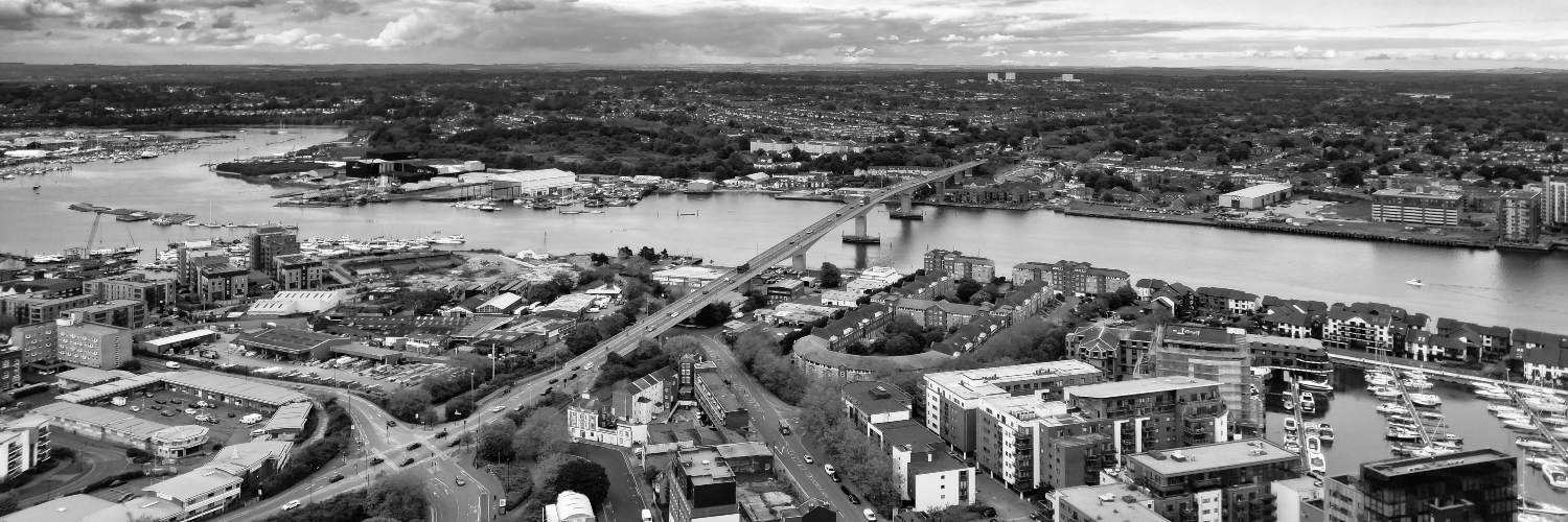Black and white photo of Southampton city featuring a river and a bridge, showcasing urban architecture and landscape.