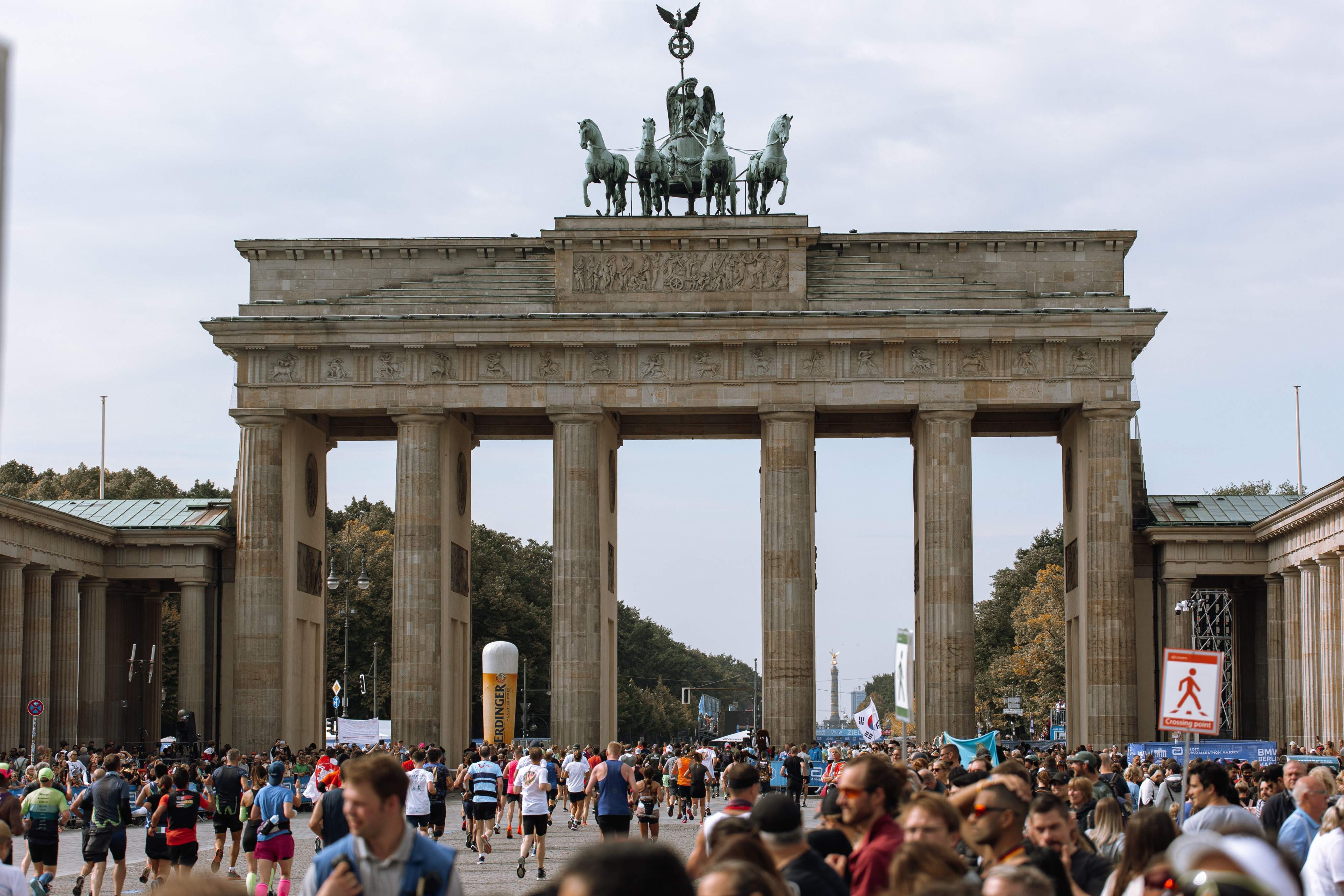 A large crowd of participants walking past a historic building during the Berlin Marathon weekend festivities.